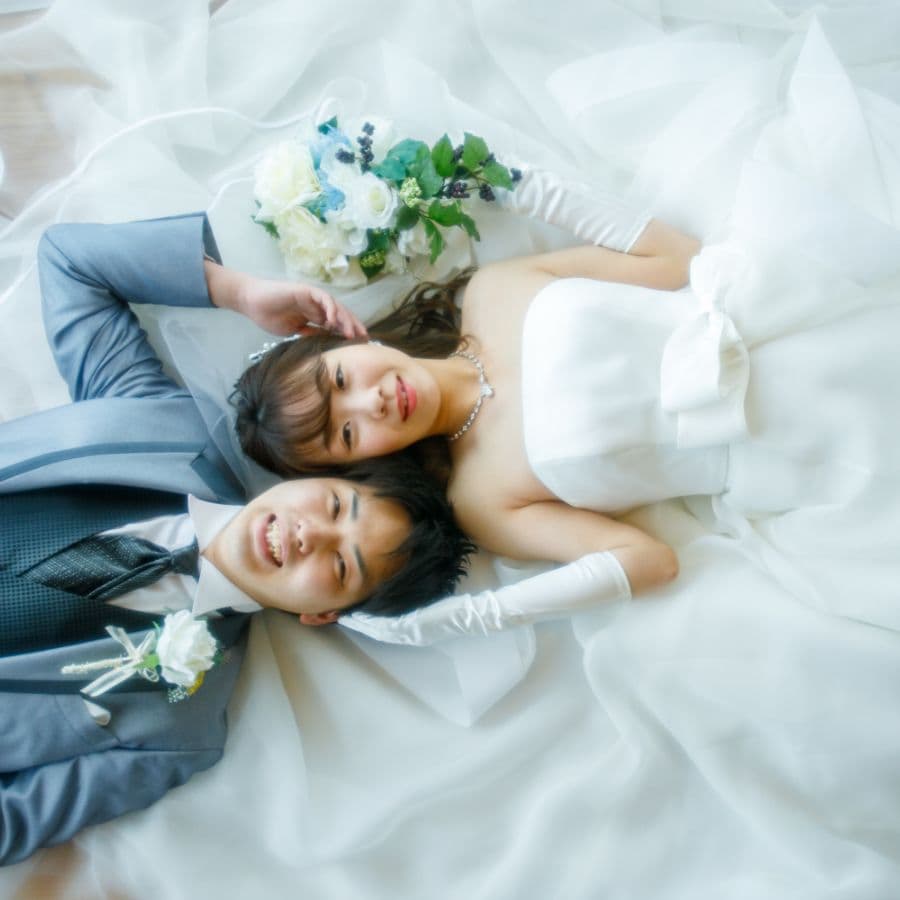 スタジオにて寝転がっている新郎新婦を上から撮影