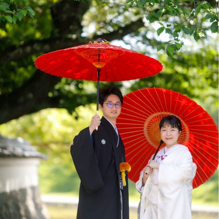 五十鈴川沿いにて和装新郎新婦赤い傘を持って
