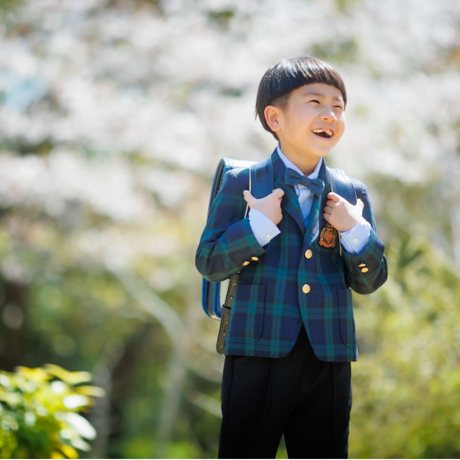 桜をバックにランドセルを背負った男の子