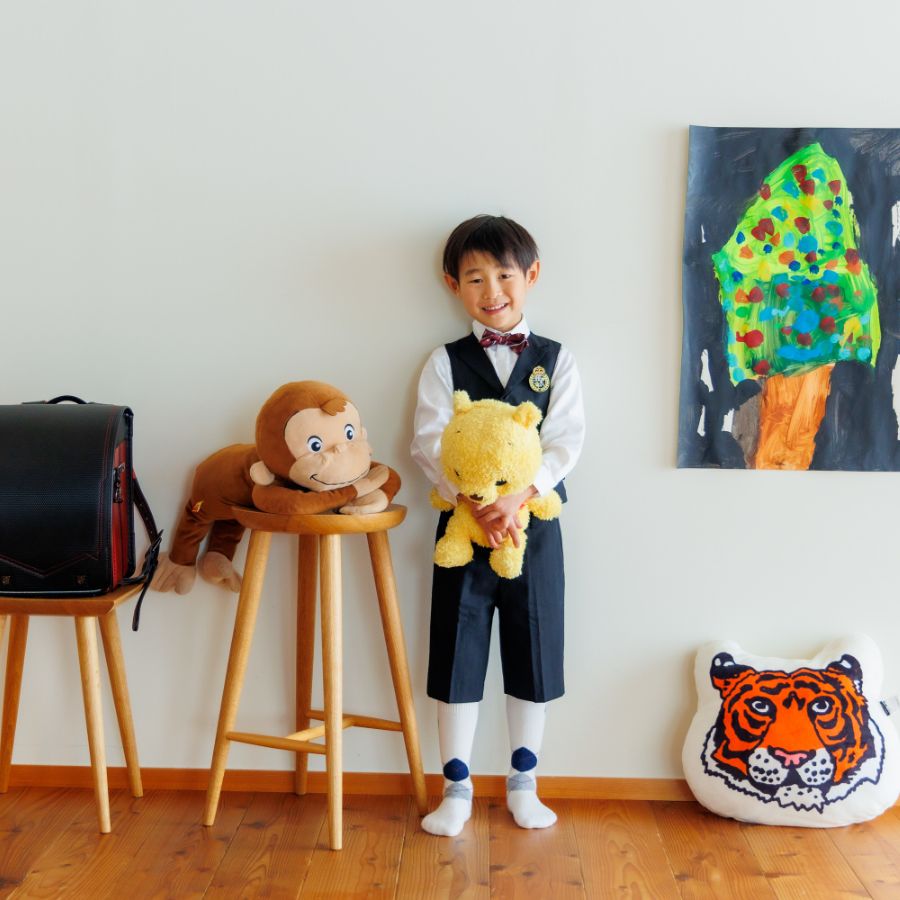 好きなぬいぐるみや描いた絵をバックに立つ男の子