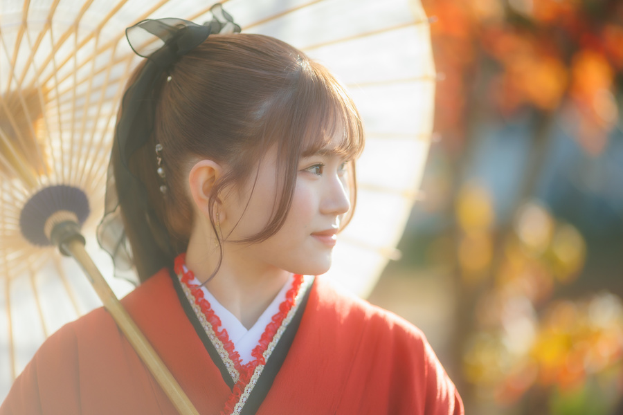 二十歳の記念写真　女性赤い振り袖　白い和傘をさしている半身横向き写真