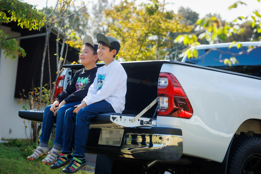 男の子兄弟2人　車の後ろの荷台に座っている