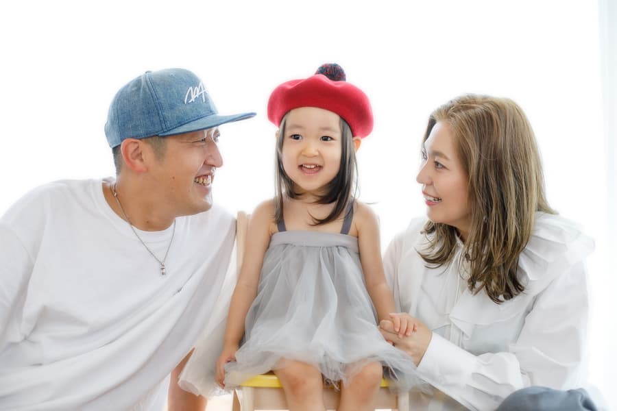 赤い帽子をかぶった3歳女の子　パパとママに見守られて