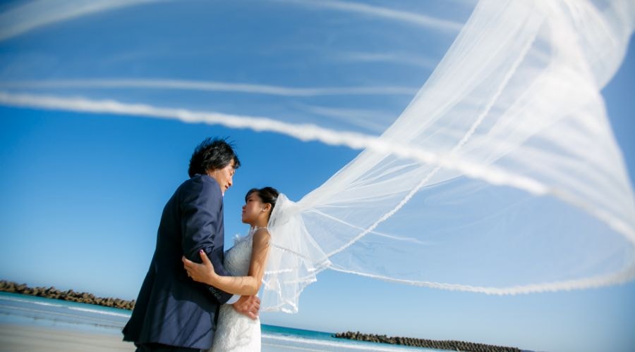 国府海岸にて　新郎新婦向かい合いベールが風になびいている