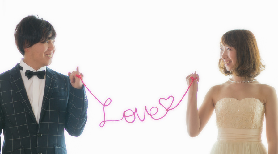 新郎新婦が赤いLOVEの糸で結ばれている