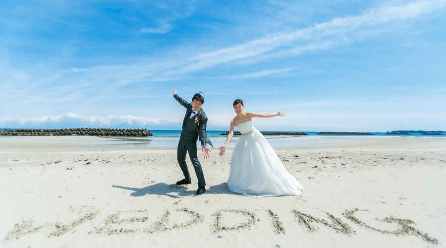 志摩市国府海岸にて　ドレス姿の新郎新婦　前にWEDDING　の文字