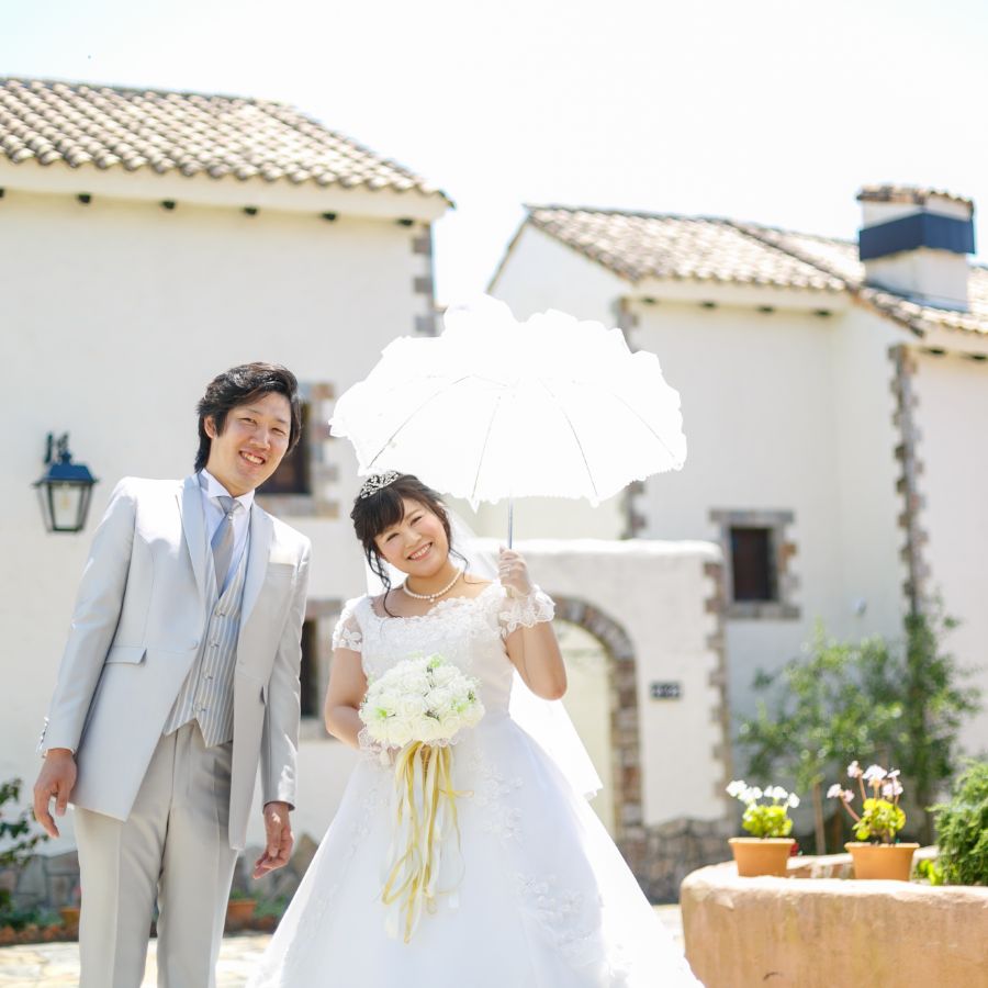 地中海村の街並みの中新郎新婦相合傘で