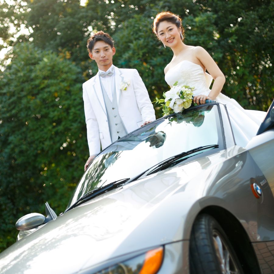 オープンカーの座席のところに立つ新郎新婦