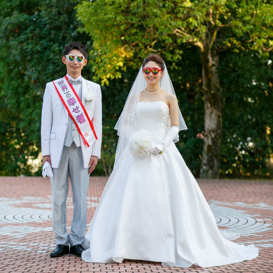 新郎新婦ハートのサングラスをかけて、新郎の方には世界一の幸せ者のタスキがかけられている